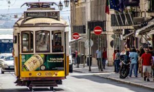 Image of tram number 12 in Lisbon driving down a crowded street, Golden Visa announcement 2023 | getNif