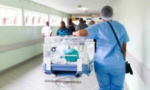Image of nurse walking down a Portuguese hospital hallway wheeling a box of medicinal items, Portuguese healthcare | GetNif