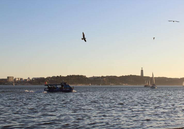 Image of river in Lisbon with boat containing digital nomads in Portugal on a sunset boat trip, seagulls flying, GetNif