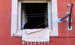 Black cat in window of orange house, blanket hanging outside of window. Personal income tax rates Portugal | GetNif
