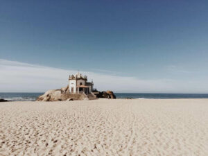 Image of the Algarve region with sandy white beach and a Portuguese property on beach front in background | GetNif