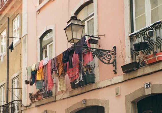 Image of a pink building with clothes out to dry hanging from balcony, lampshade juts out of building, real estate investment Golden Visa | GetNif