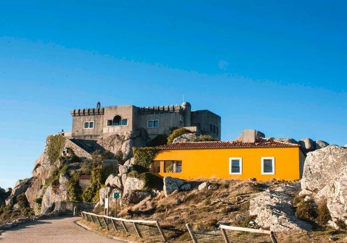 Image of yellow Portuguese bungalow house on a hill with castle like monument in background, Portugal digital nomad visa | getNif