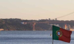 Image of Portuguese flag waving April 24 bridge in background. Income tax rate in Portugal | GetNif